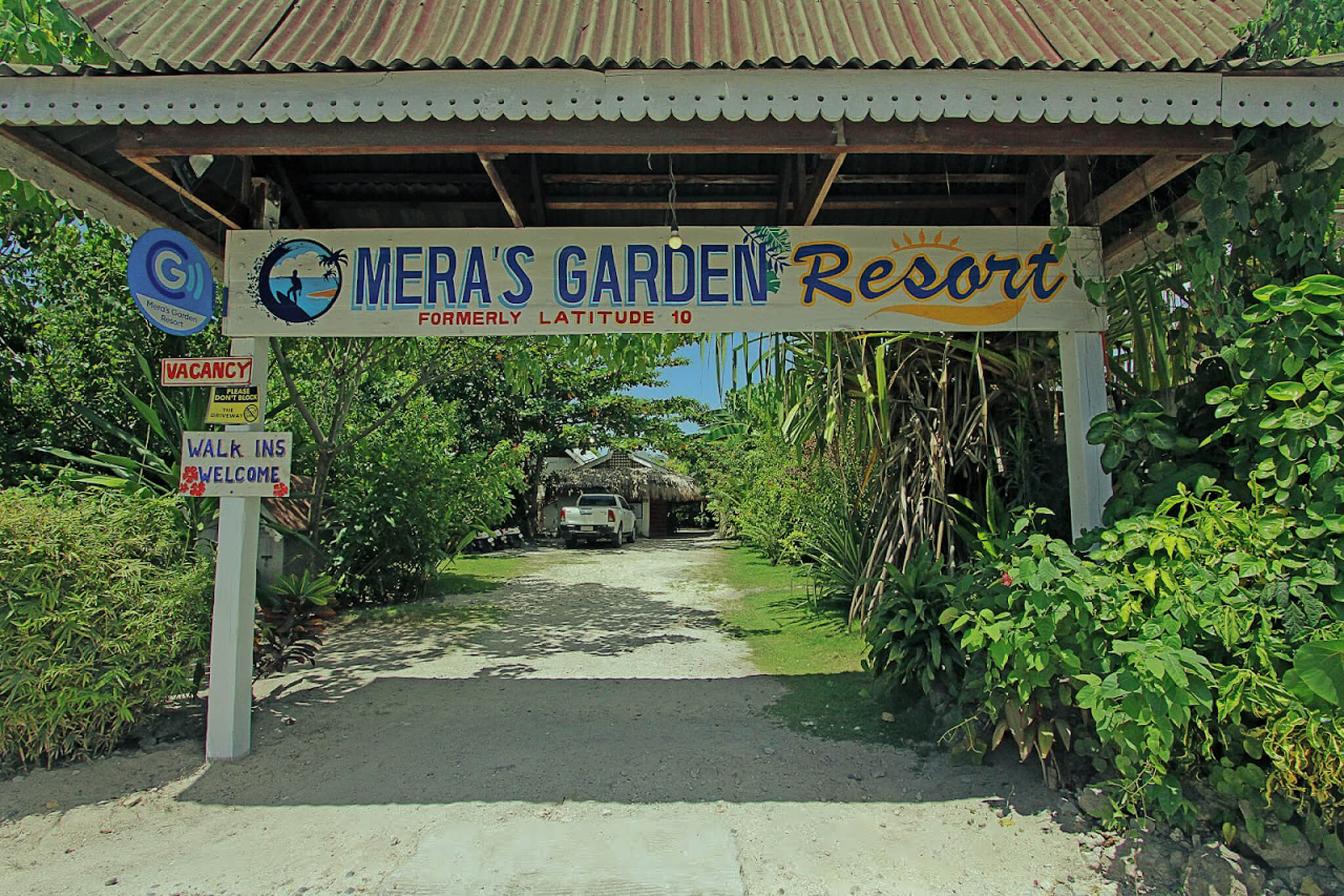 A serene cinema garden resort featuring lush greenery, comfortable seating, and a large outdoor screen for movie viewing.